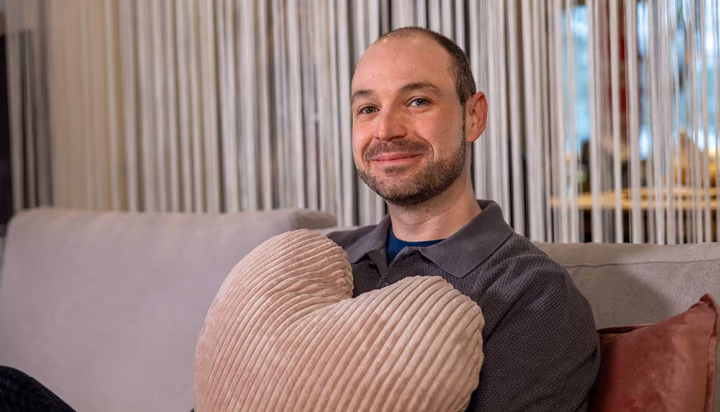 Helles Wohnzimmer mit grauem Ecksofa und Relaxsessel, dekoriert mit bunten Kissen, Pflanzen und Teppich im skandinavischen Stil – modernes Sofa-Design für gemütliches Wohnen.